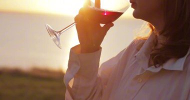 Gün batımında şarap içen kadın.