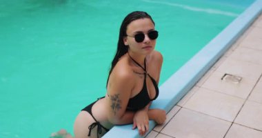 Havuzda siyah bikinili seksi kadın, ağır çekimde.