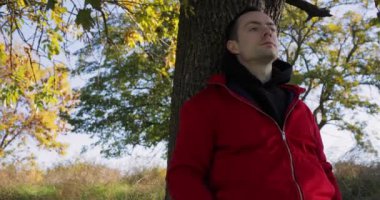 Bir adam pozitif enerji almak için donör ağacına yaslanır.