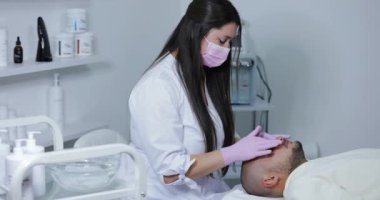 Kozmetik uzmanı güzellik salonunda erkekler için yüz ameliyatı yapıyor.