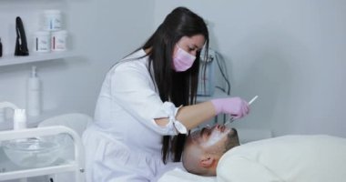 Kozmetik uzmanı güzellik salonunda erkekler için yüz ameliyatı yapıyor.