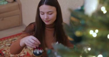 Bir kadın Noel ağacına süslemeler asıyor.