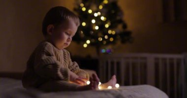 Küçük çocuk Noel 'den önce evde çelenkle oynuyor.