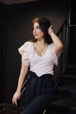 Klasik takım elbiseli zarif bir kadın merdivenlerde poz veriyor.