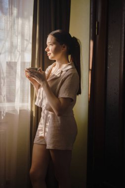 Sabahları pencerenin yanında çay içen bir kadın.