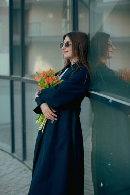 Baharda şehir caddesinde lale çiçekleri tutan mutlu kadın.