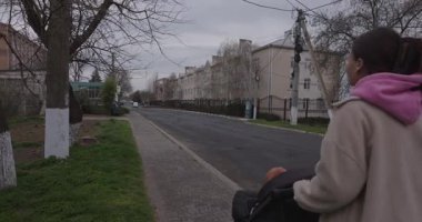 Genç anne bir bebek arabasıyla sokakta yürüyor.