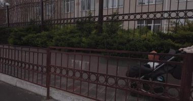 Genç anne bir bebek arabasıyla sokakta yürüyor.