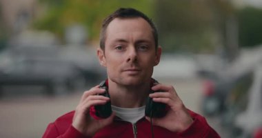 Kulaklık takan bir adam şehir caddesinde durmuş müzik dinliyor.