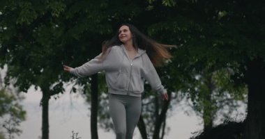 Mutlu kadın yağmurlu bir günde parka dönüyor, ağır çekimde.