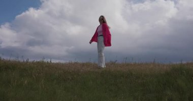 Minimalizm, pembe elbiseli kız çayırda koşar bulutlara