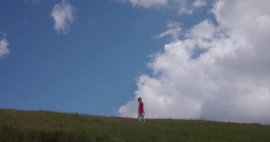 Minimalizm, özgürlük kızı bulutların arkasında elleri havada bir tepede dönüyor.