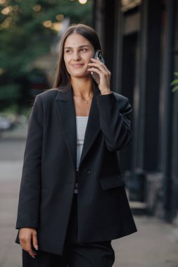 Şehir caddesinde akıllı telefonla konuşan zarif bir iş kadını.