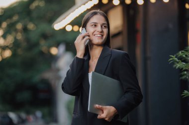 Şehir caddesinde akıllı telefonla konuşan zarif bir iş kadını.