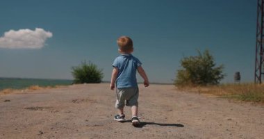 Huzursuz bir çocuk deniz iskelesinde yürüyor.