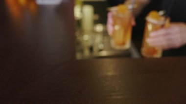 Barmen elleri barın tezgahına portakal kokteyli ve kurutulmuş kayısı koyar.