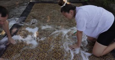 Bahçedeki halıyı elle yıkıyorum.