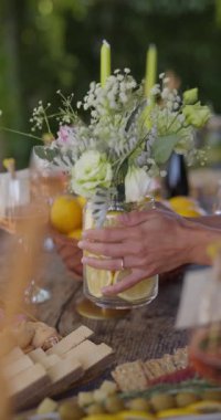Bir kadın bir vazo çiçek ve limonu masanın üstüne koyar, dikey bir video.
