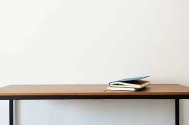Defterler ahşap masada, minimalist iç mekan. Ya çalış ya da okula geri dön.