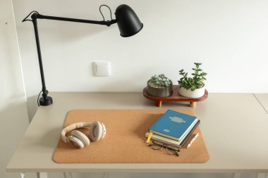 Lamba, defterler, kulaklıklar ve sulu bitkilerle modern minimalist çalışma alanı. Üretkenliği, uzaktan çalışmayı, günlüğü, farkındalığı ve rahat iç mekanı kavramsallaştır.
