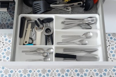 Çatal bıçak ve çatal bıçaklarla dolu düzenli mutfak çekmecesi, üst manzara. Mutfak çekmecesi, çatal bıçak takımı ve plastik tepside mutfak gereçleri. Bıçaklar, çatallar, kaşıklar, tirbuşon, soyucu. Organizasyon, temizlik ve ev hayatı kavramı.