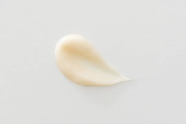 Beyaz arka planda bej krem lekesi kozmetik cilt dokusu, minimal yakın plan. Nemlendirici, losyon, serum, şampuan, saç kremi veya temel