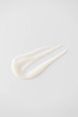 Beyaz arka planda pürüzsüz beyaz krem ya da losyon örneği. Kremsi doku cilt bakım ürünü, yüz nemlendirici.