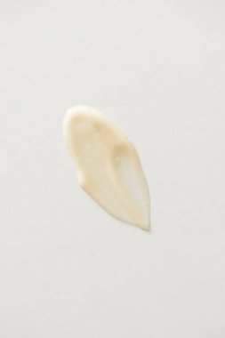 Beyaz arka planda kozmetik retinol kremi dokusu. Bej rengi minimal cilt ürünleri, dikey görüntünün üzerinde