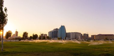 Bakü. Azerbaycan. 09.19.2921. Gün batımında bulvarın çimlerini sulamak..