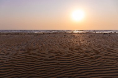 Güneşin doğuşunda deniz kenarında güzel kum dokusu.