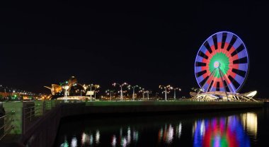Bakü. Azerbaycan. 09.25.2021. Milli bayrağın aydınlatıldığı bulvarda dönme dolap..