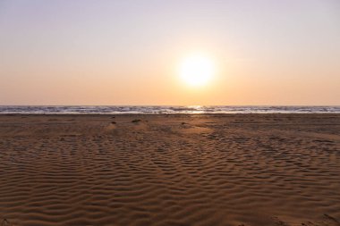 Güneşin doğuşunda deniz kenarında güzel kum dokusu.
