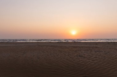 Güneşin doğuşunda deniz kenarında güzel kum dokusu.