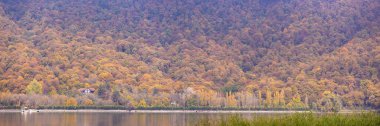 Garanohur Gölü. Gabala bölgesi. Azerbaycan. 10.31.2021. Dağda sarı ağaçları olan gölde bir ev..