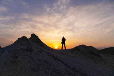 Kameralı bir fotoğrafçı gün batımında çamur volkanlarının fotoğraflarını çeker..