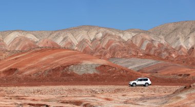 Khizi bölgesi. Azerbaycan. 04.17.2022. Güzel kırmızı dağlarda beyaz araba.