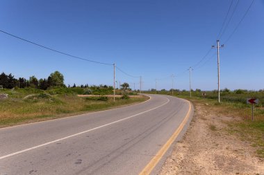 Kırsal bir asfalt yol sola dönüyor..