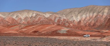 Khizi bölgesi. Azerbaycan. 04.17.2022. Güzel kırmızı dağlarda beyaz araba.