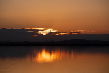 Sessiz bir gölde güzel sarı gün batımı.