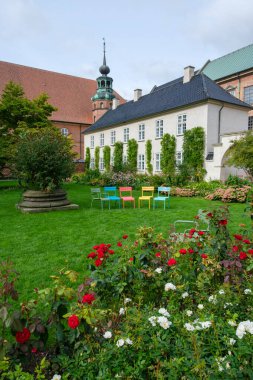 Kopenhag, Danimarka 3 Ekim 2023 - Kraliyet Kütüphanesi Bahçesi, Slotsholmen, Kopenhag 'daki çiçeklerin arasında çimenlerin üzerinde gökkuşağı renginde beş sandalye