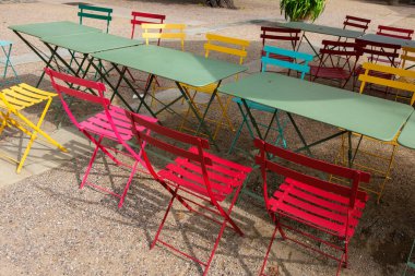 Renkli bir gökkuşağında katlanan koltuklar - kırmızı, mavi, sarı ve yeşil masalar tarafından rastgele yerleştirilir.