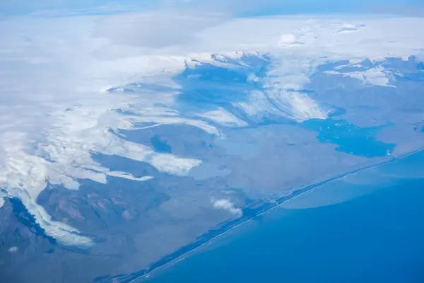 Glaciers of Iceland\'s Vatnajokull Ice Sheet and the Jokulsarlon glacial lake dotted with icebergs from plane coming into land at Keflavik