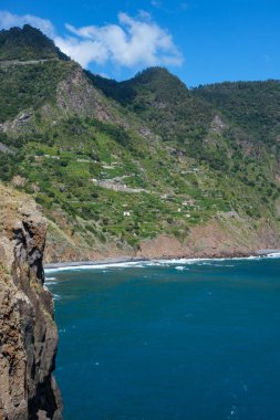 Building, road and cultivated land pepper the steep cliffs of Northern Madeira Island near the Miradouro Guindaste Faial, Portugal clipart