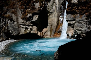 Uçurumun tepesindeki siluetli adam Nilgiri nehrine akan şelale havuzu, Annapurna Kuzey Ana Kamp Yolu, Nepal