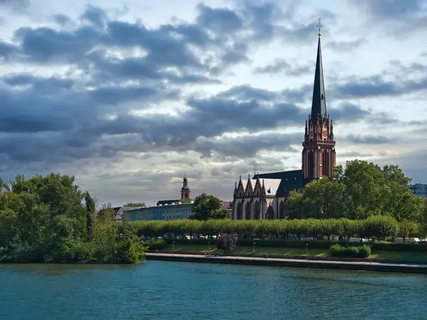 Frankfurt 'taki Üç Kralın Evanjelik Kilisesi Bulutlu bir gökyüzü ve önplanda nehir