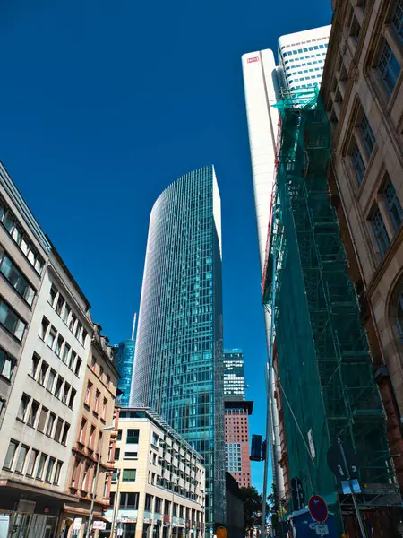 stock image A skyscraper in the background, where in the foreground are lower old flat buildings under the clear blue sky.