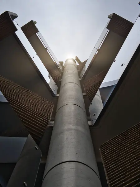 Soyut bir fotoğraf, bir tüp, yukarı doğru aynalı yüzeyler, sağ, sol ve modern mimari güneşli bir ortamda.
