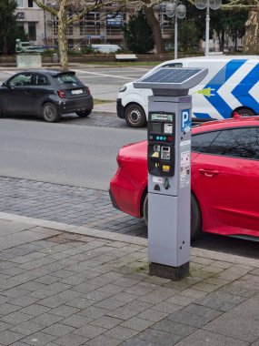 Yolun sağ tarafında güneş paneli olan arabalar için kırmızı, siyah ve beyaz bir minibüs olan bir bilet makinesi var.
