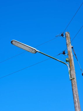 Mavi gökyüzü arka planında bir elektrik direğinin dikey çekimi