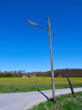 Mavi gökyüzü arkaplanının altında bir elektrik direğinin dikey çekimi